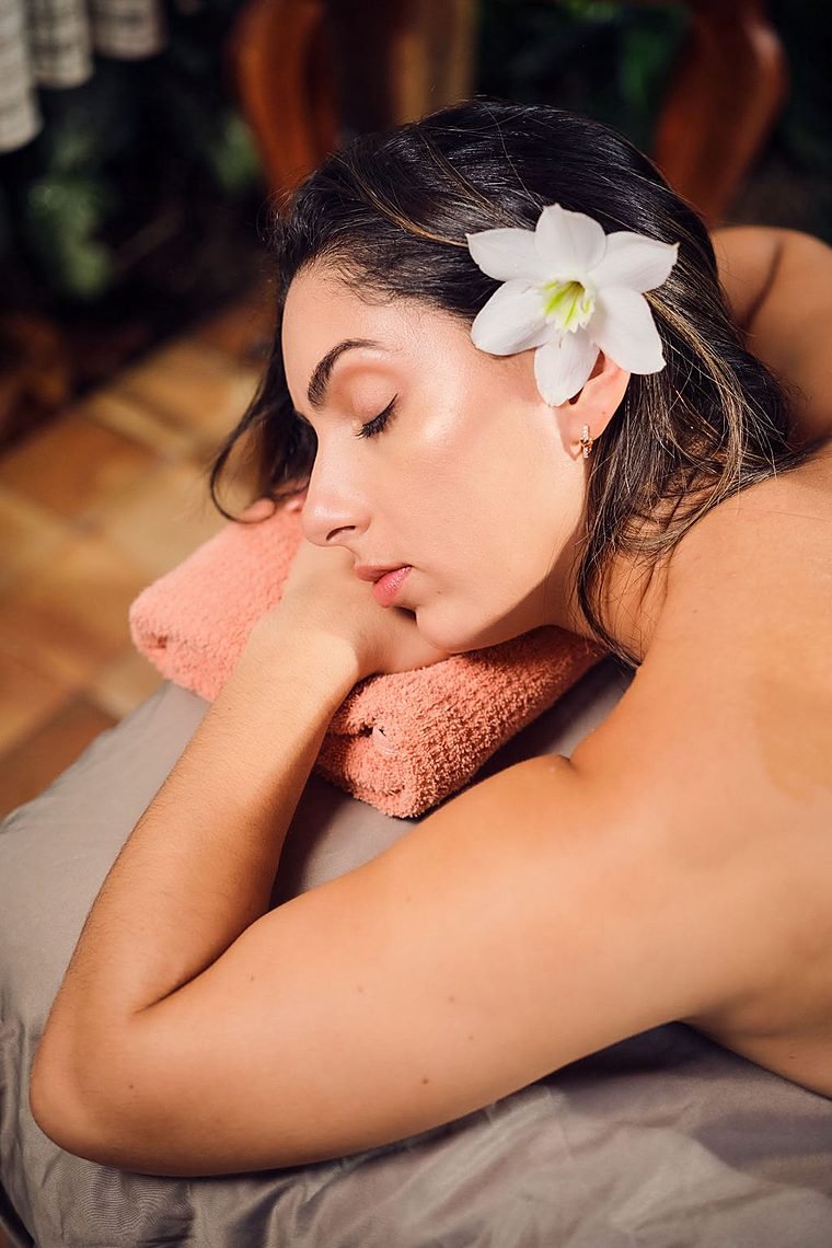 Guest relaxing on the massage table with a white flower in her hair