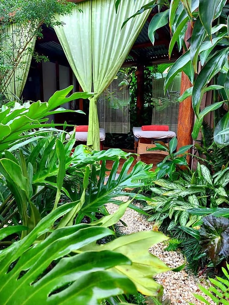 Massage tables with green curtains among tropical plants