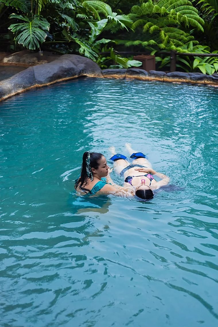 Therapist supporting a guest who floats on her back in warm water